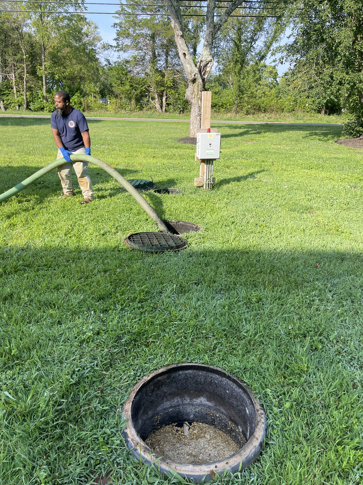 Technician pumping out a septic tank in a residential yard for maintenance.