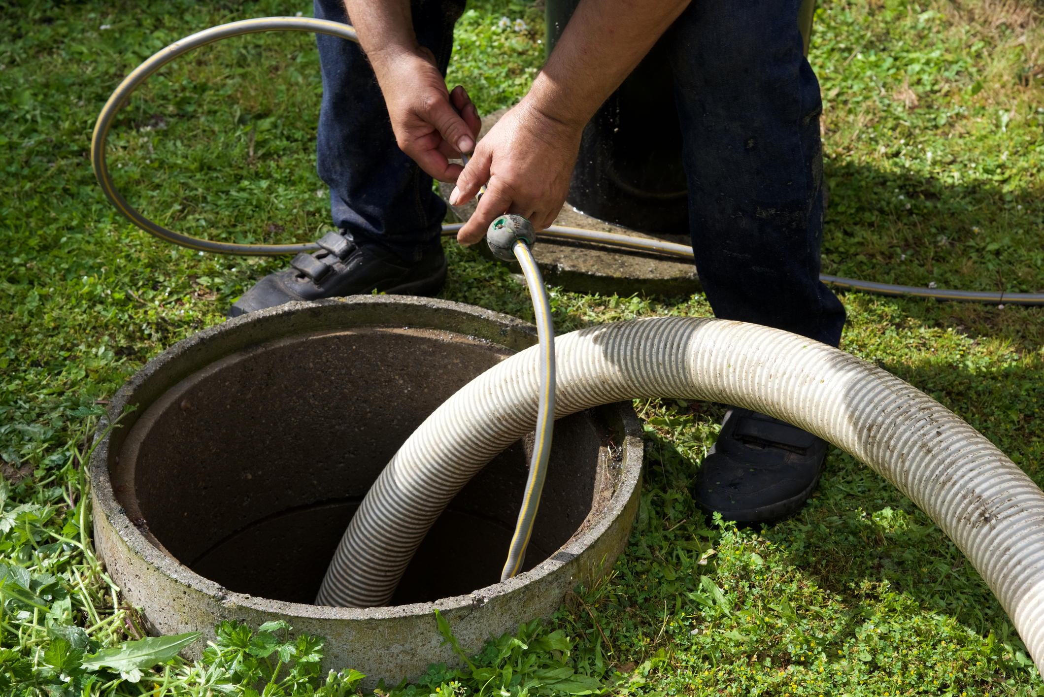 Technician inspecting and preparing septic tank for pumping