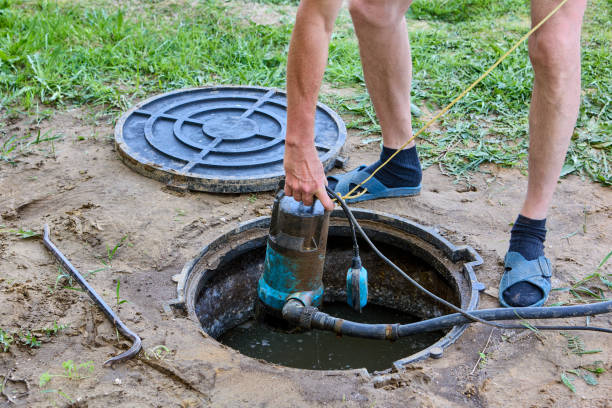 Worker using a pump to empty a septic tank at a residential property
