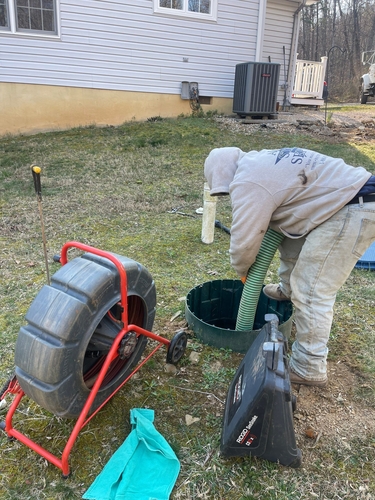 Technician performing quarterly septic pumping service at residential site