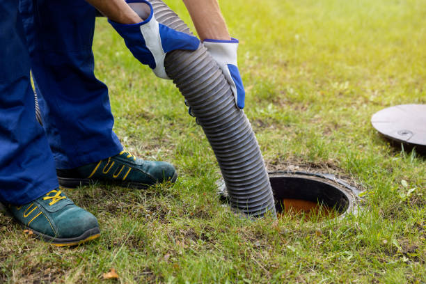 Technician inserting vacuum hose into ground septic tank access