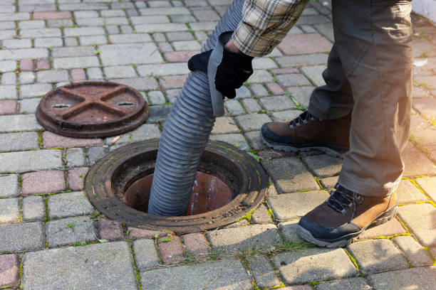 Technician performing annual septic pumping through manhole cover