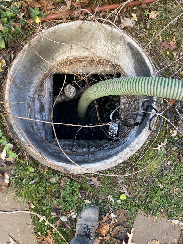 Green vacuum hose inserted into septic tank for routine pumping